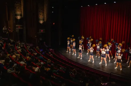 Smith cheerleaders in Mendenhall auditorium, pom poms raised above their heads