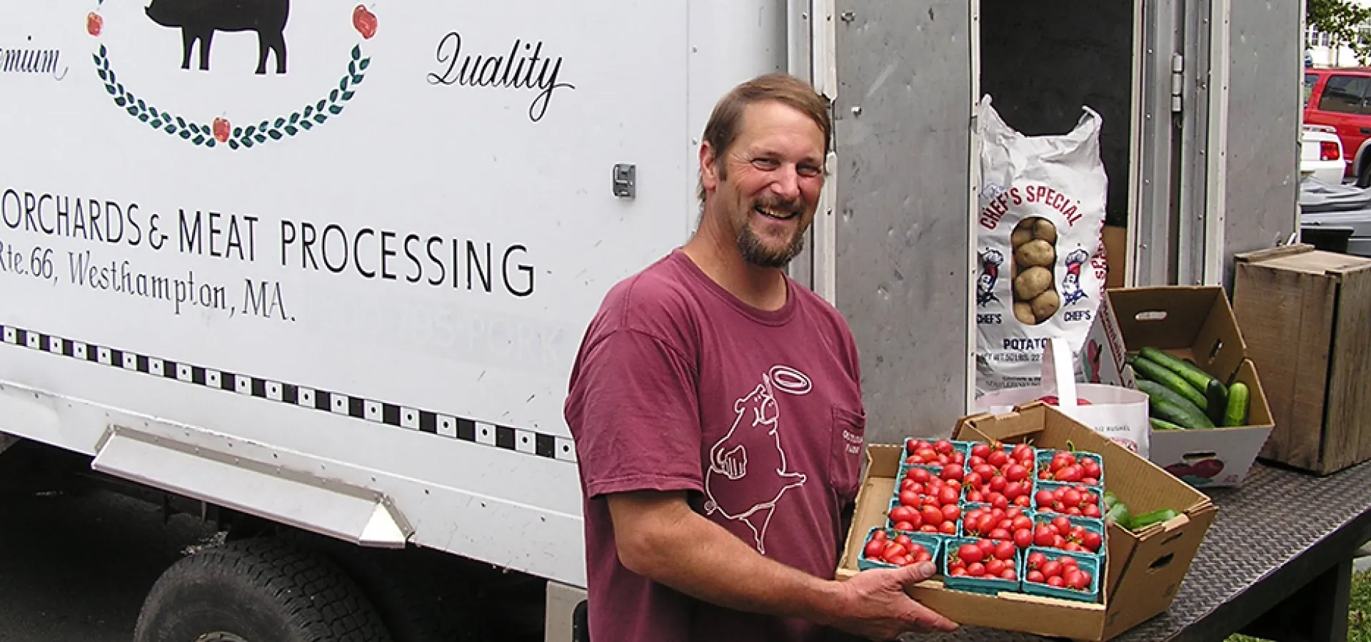 Man from local farm displays his fresh tomatoes from the back of a truck