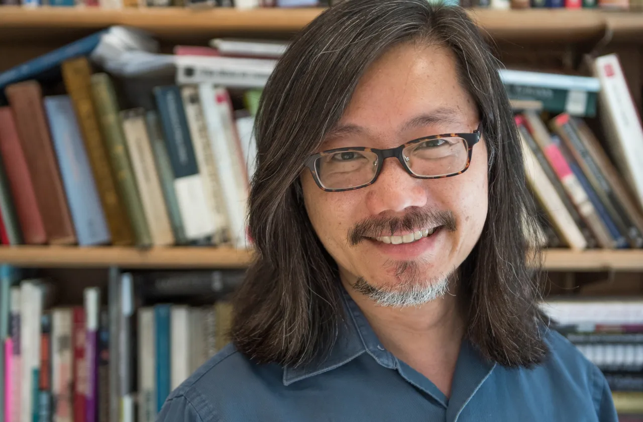 Floyd Cheung in front of a bookshelf.