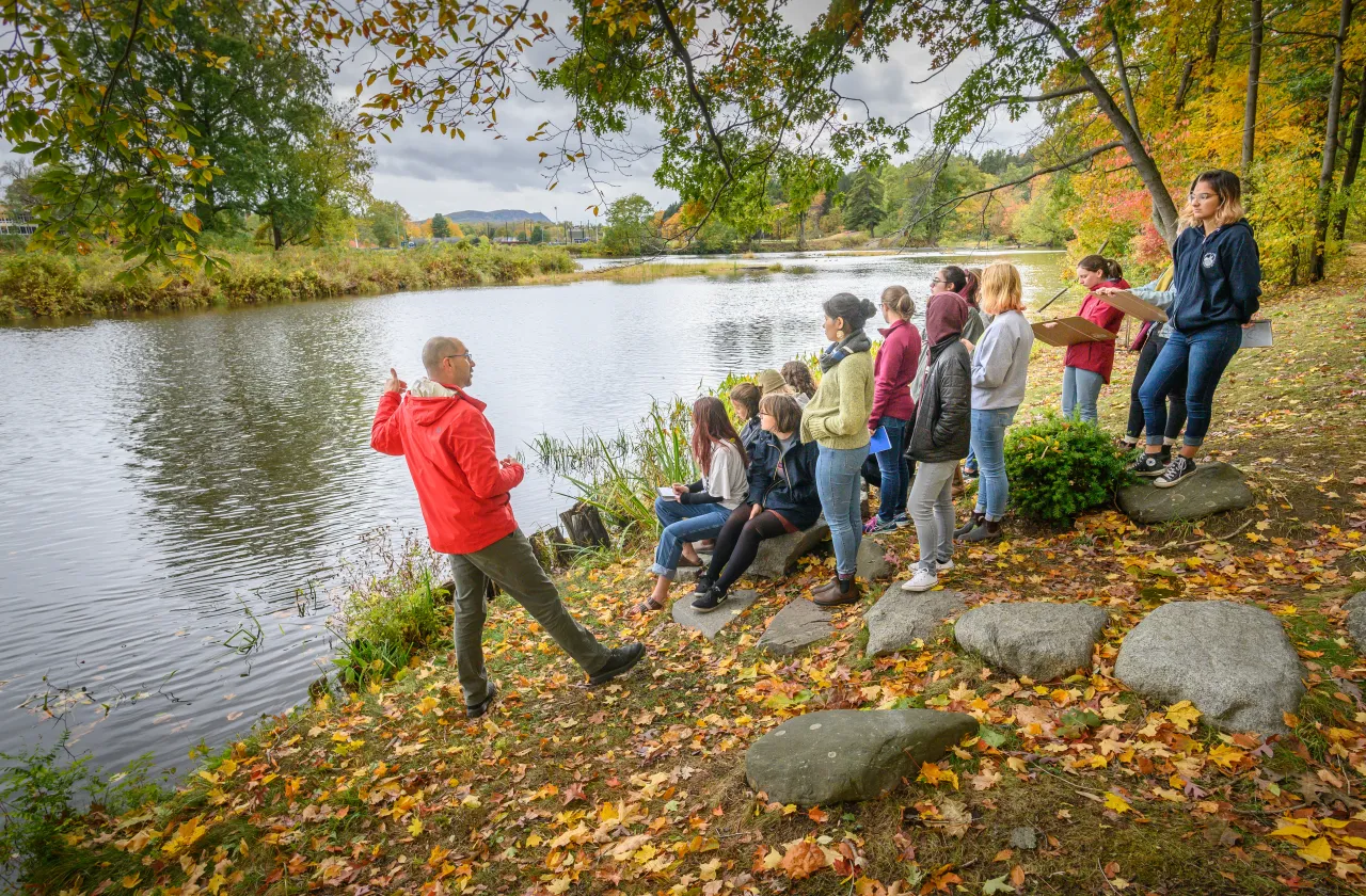 Students listening to a lecture near the Mill River.