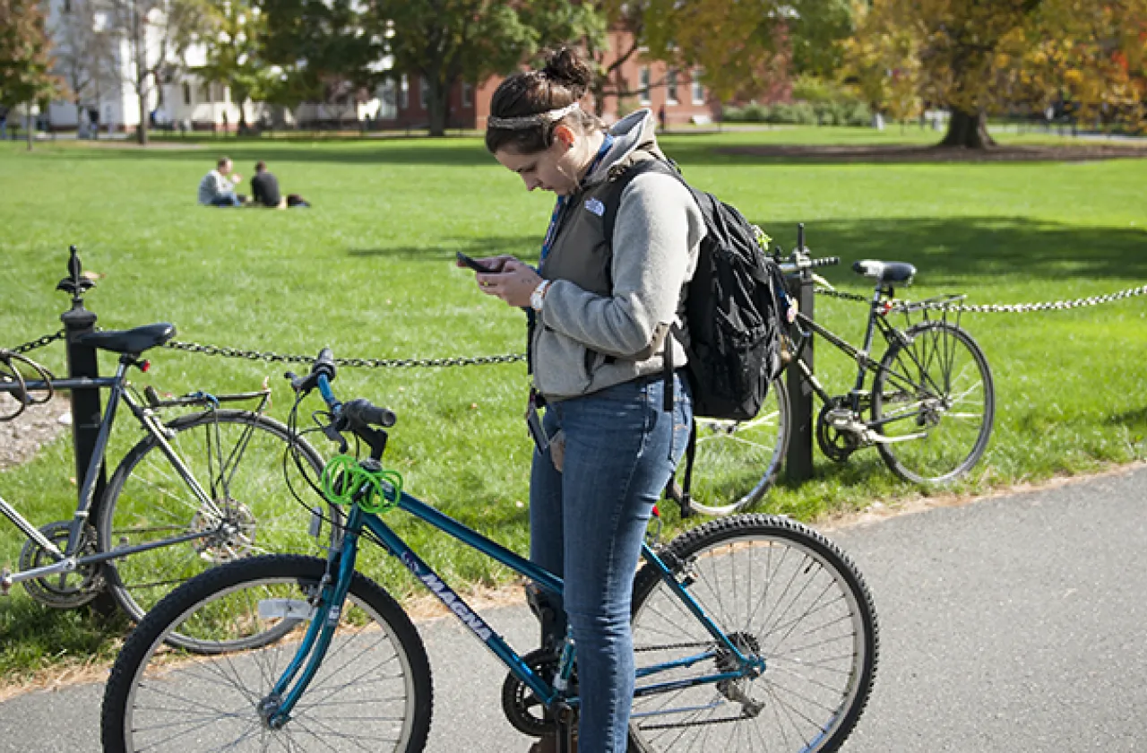 Girl looking at cellphone while riding a bike