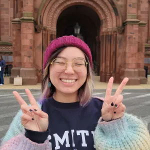 Cloud Osmond ’24 smiling making peace signs outside the Smithsonian