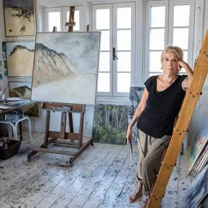 Barefoot Anne Peretz in her studio, surrounded by paintings and easels