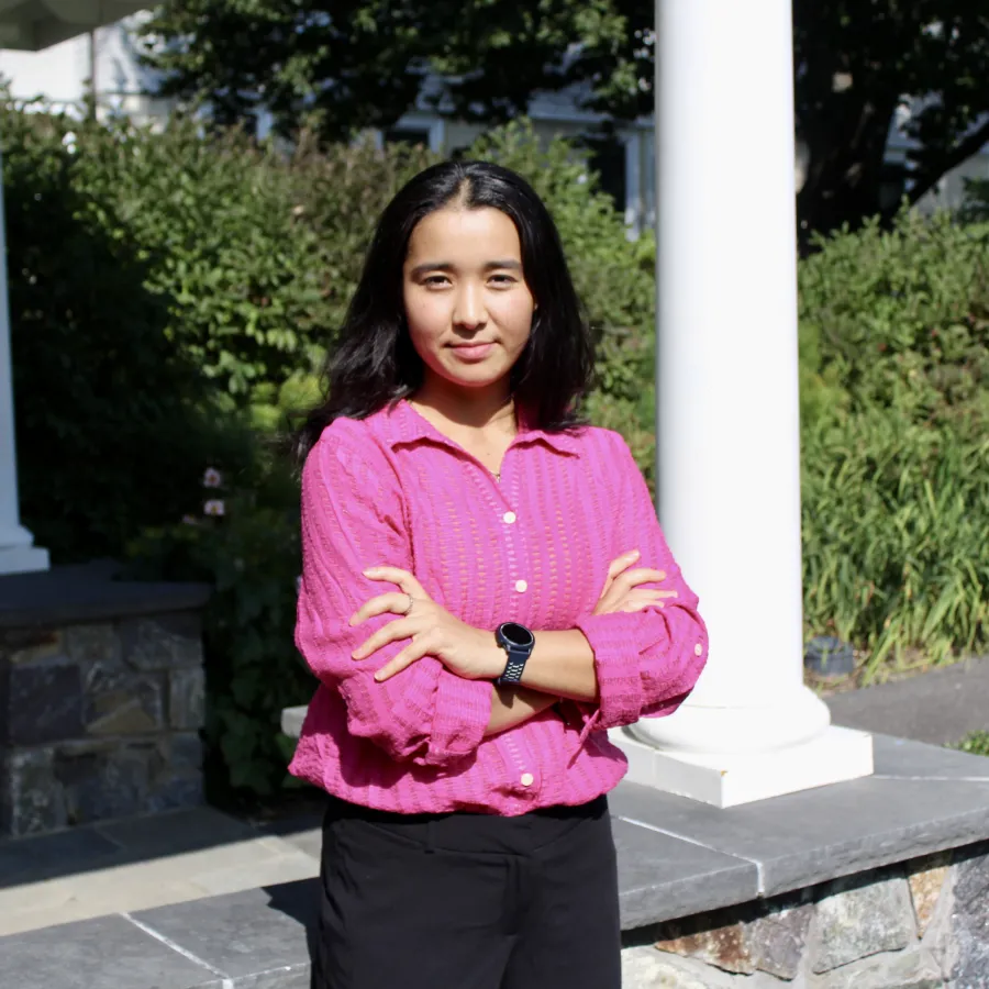 Nadira Talayee wears a pink top and looks at the camera with crossed arms. Portrait by Brooke Chandler ’25