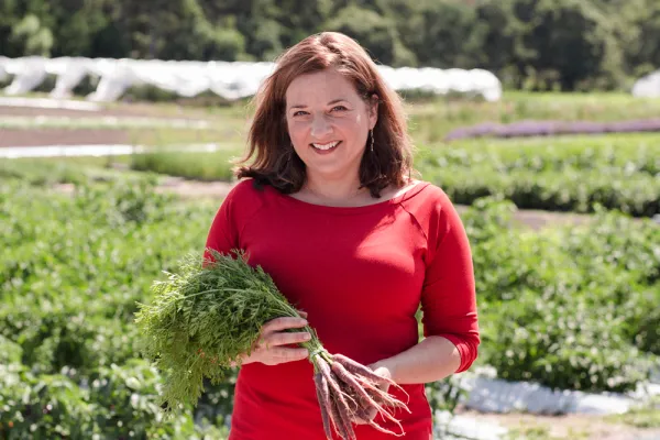 Amy Traverso holding a bunch of carrots outside at a nursery