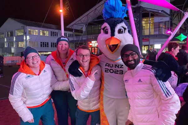 Valerie Love standing with the FIFA mascot and two other volunteers.