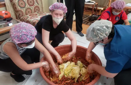 Students adding vegetables to kimchi