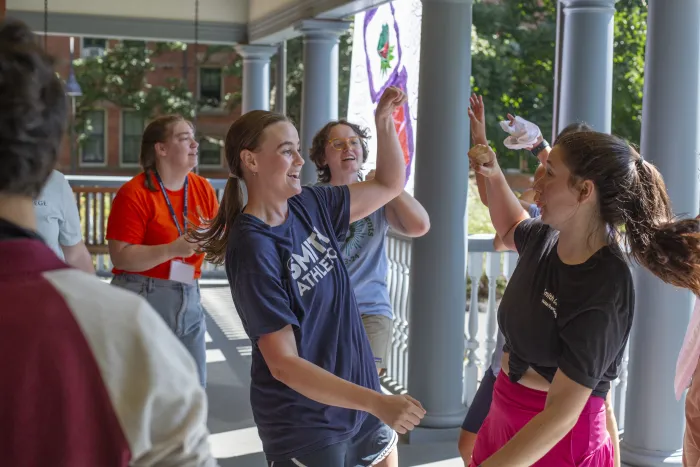 Student leaders dance on the porch of a house during move-in