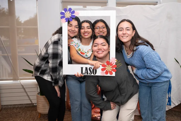 A group of students holding up a giant picture frame that says "LASO," short for "Latin American Students Organization" on it.