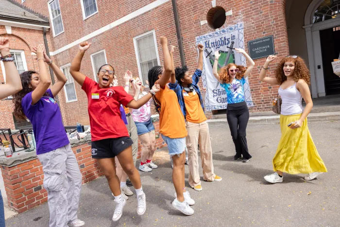 A group of students joyfully jumping in the air with their arms lifted above their head