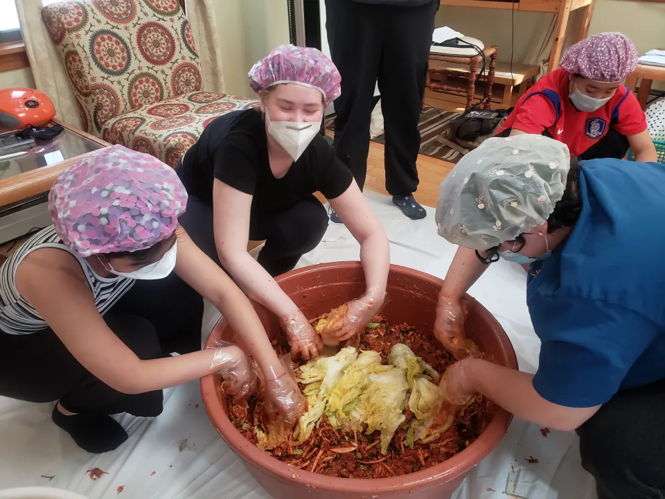 Students adding vegetables to kimchi