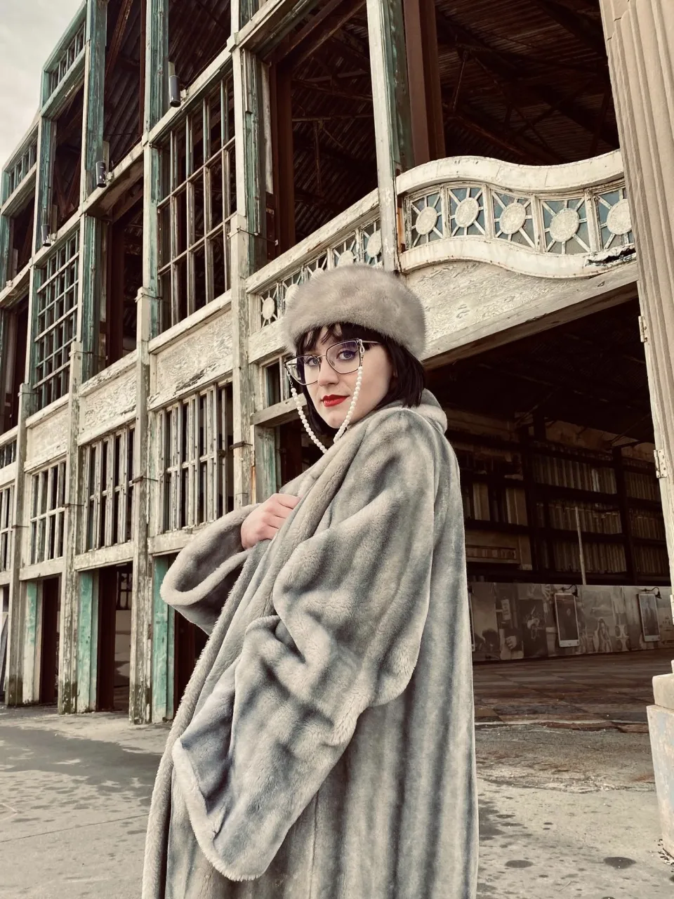 Vivian DeRosa in a fur coat outside an older building with an ornate railing